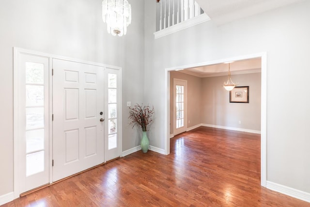 entrance foyer featuring ornamental molding, wood-type flooring, and a notable chandelier