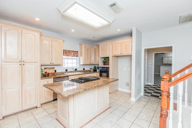 kitchen featuring sink, stainless steel appliances, light tile patterned floors, light stone counters, and a kitchen island