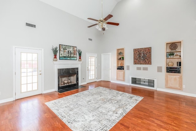 living room featuring built in shelves, ceiling fan, a fireplace, and high vaulted ceiling