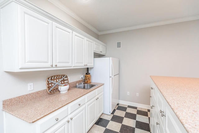 kitchen featuring white refrigerator, crown molding, white cabinetry, and sink