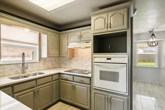 kitchen with white oven, black electric stovetop, crown molding, sink, and decorative backsplash