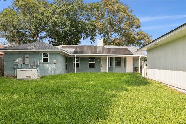 rear view of property with solar panels and a lawn