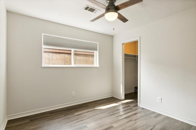 unfurnished bedroom featuring ceiling fan, light hardwood / wood-style floors, a spacious closet, and a closet