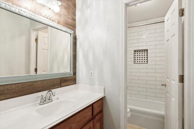 full bathroom featuring vanity, toilet, tiled shower / bath, and wooden walls