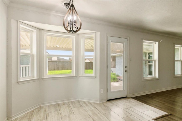 doorway to outside with ornamental molding, light hardwood / wood-style flooring, and a chandelier