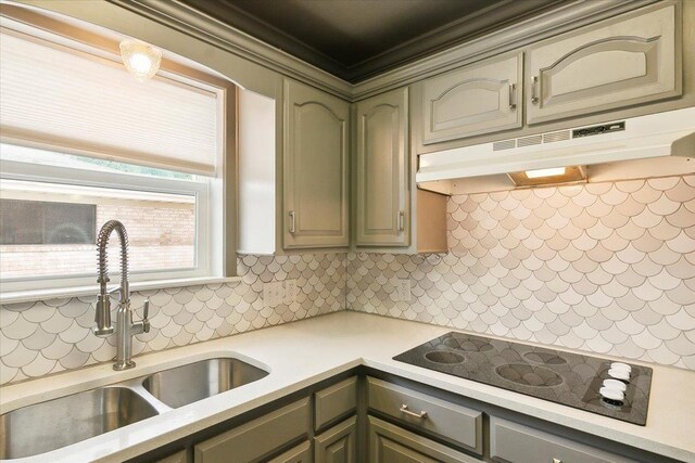 kitchen with black electric stovetop, ornamental molding, sink, and tasteful backsplash