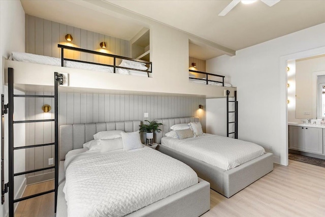 bedroom featuring ceiling fan, sink, light wood-type flooring, and ensuite bathroom