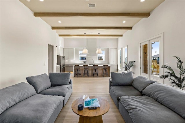 living room with beamed ceiling and light wood-type flooring