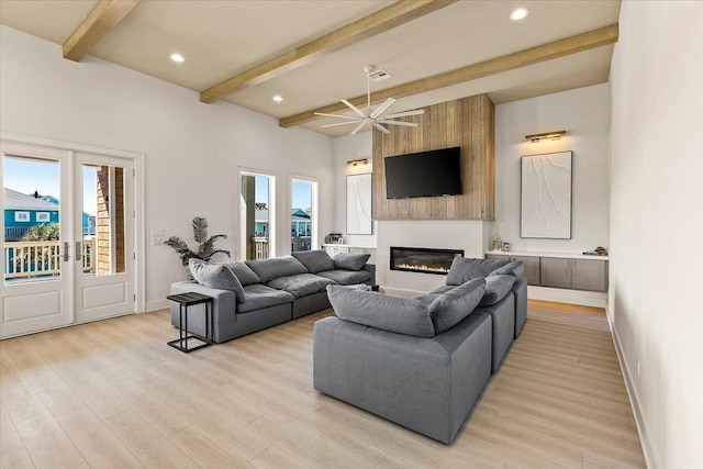 living room with a fireplace, ceiling fan, beamed ceiling, light hardwood / wood-style floors, and plenty of natural light