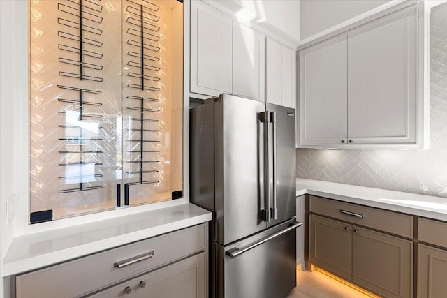 kitchen with gray cabinetry, high end fridge, and tasteful backsplash