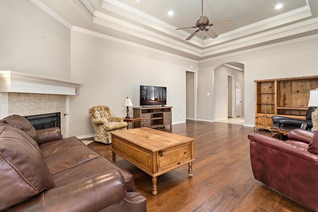 living room with a tray ceiling, dark hardwood / wood-style flooring, ceiling fan, and a fireplace