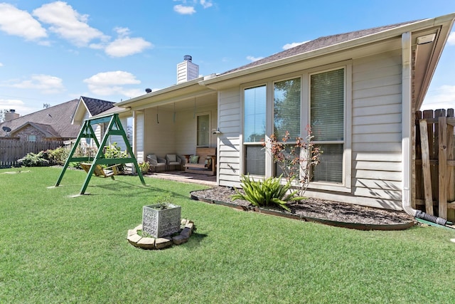 back of property with a yard and a playground