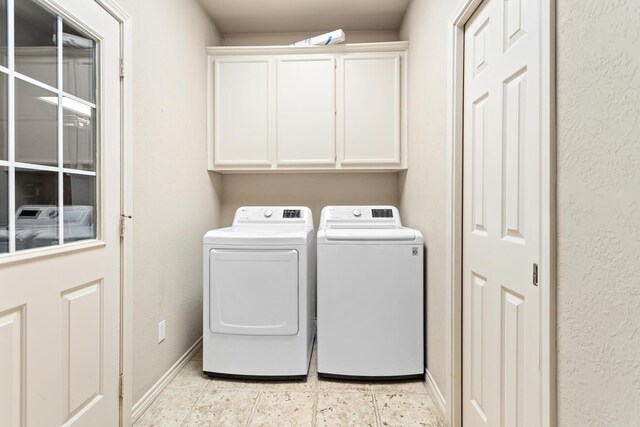 laundry area with cabinets, light tile patterned floors, and washer and clothes dryer