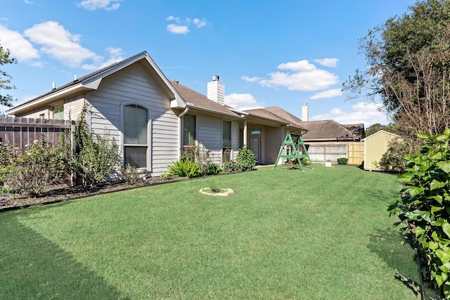 rear view of property featuring a yard and a storage shed