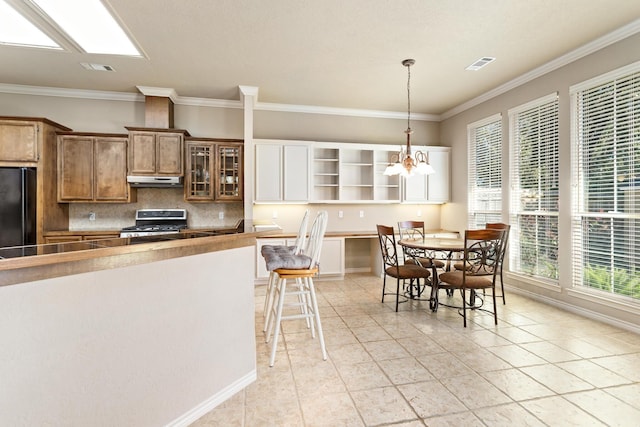 kitchen featuring an inviting chandelier, black refrigerator, light tile patterned floors, stainless steel range, and decorative light fixtures