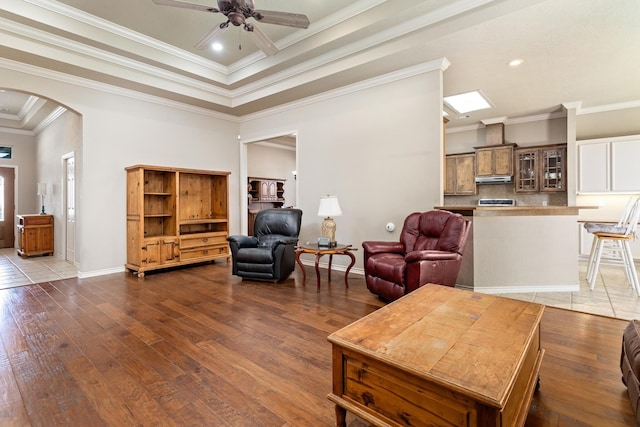 living room featuring dark wood-type flooring, ceiling fan, and ornamental molding