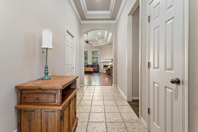 corridor featuring a raised ceiling and crown molding