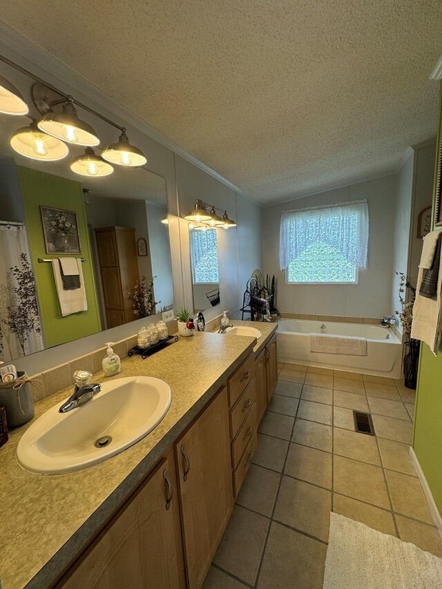 bathroom featuring vanity, tile patterned flooring, a bathtub, and a textured ceiling