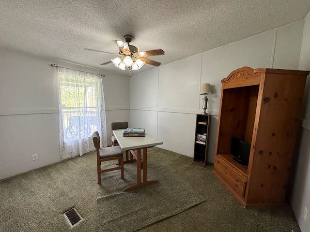 dining area featuring ceiling fan, a textured ceiling, and dark colored carpet