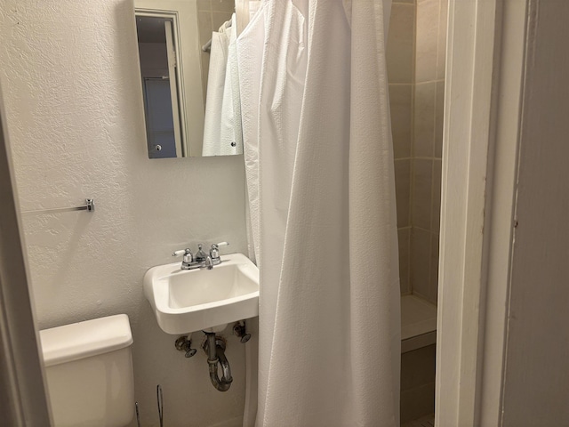 4609 Alamosa St, Port Arthur, TX 77642 - full bathroom featuring toilet, a sink, a textured wall, and a shower with shower curtain