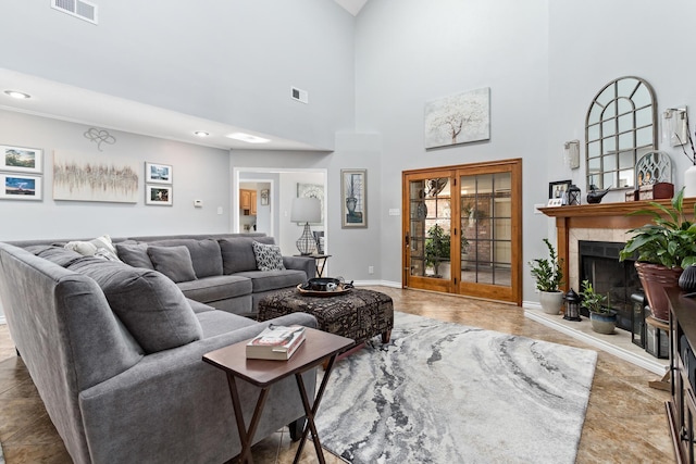 living room with french doors, a high ceiling, and a tiled fireplace