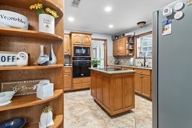 kitchen with light tile patterned flooring, backsplash, black appliances, sink, and a kitchen island