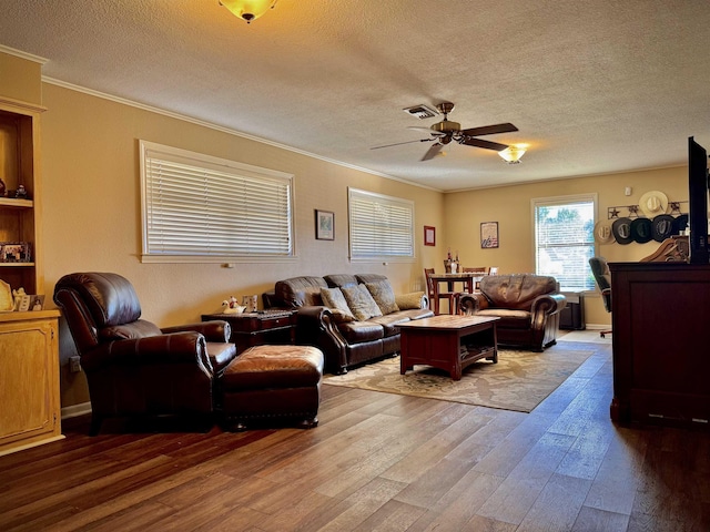 living room featuring ceiling fan, crown molding, light wood-type flooring, and a textured ceiling