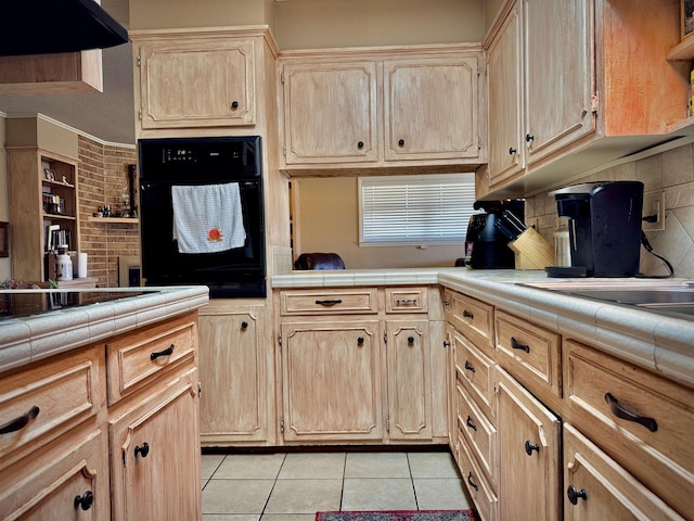 kitchen featuring tile counters, light tile patterned flooring, oven, and light brown cabinets