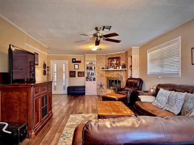 living room featuring ornamental molding, a brick fireplace, a textured ceiling, and light hardwood / wood-style flooring