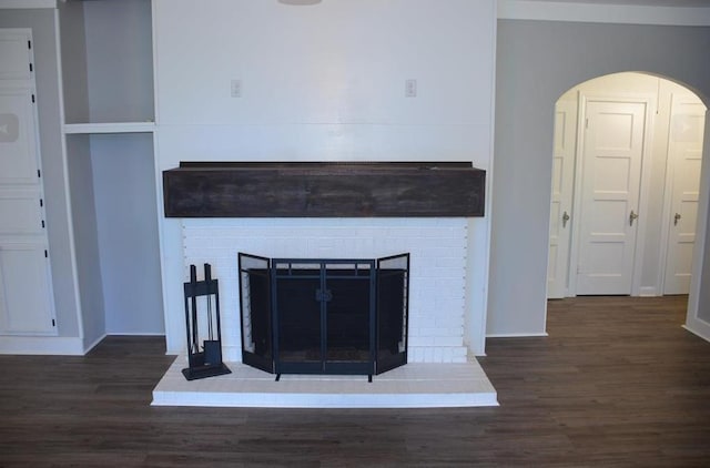 unfurnished living room with dark hardwood / wood-style flooring and a brick fireplace