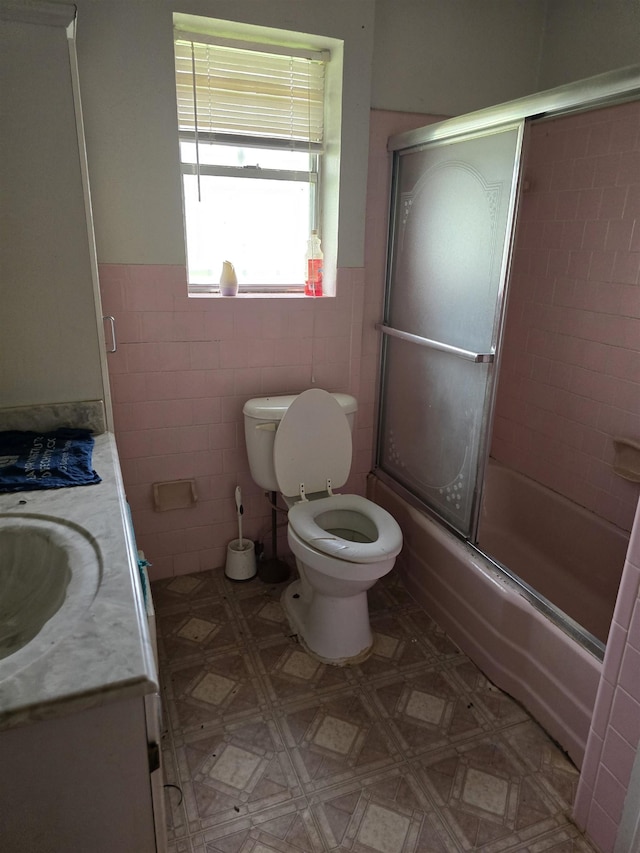 1610 Cartwright Ave, Beaumont, TX 77701 - bathroom featuring toilet, tile walls, vanity, shower / bath combination with glass door, and wainscoting