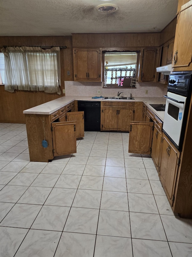 1610 Cartwright Ave, Beaumont, TX 77701 - kitchen featuring black appliances, a peninsula, light countertops, a textured ceiling, and brown cabinetry
