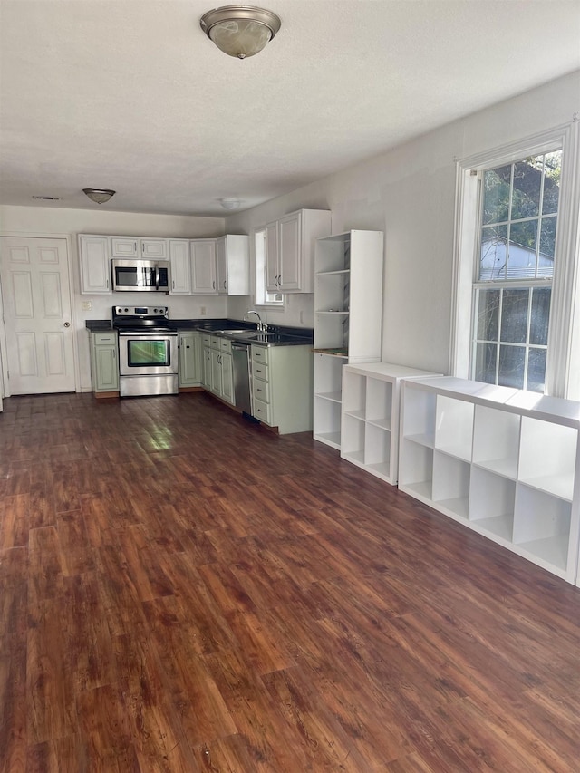 kitchen featuring stainless steel appliances, white cabinetry, dark wood-type flooring, and sink