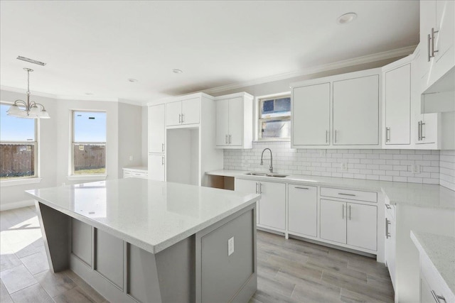 kitchen featuring sink, white cabinetry, decorative backsplash, and pendant lighting