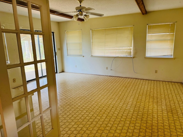 unfurnished room featuring ceiling fan, beamed ceiling, and a textured ceiling