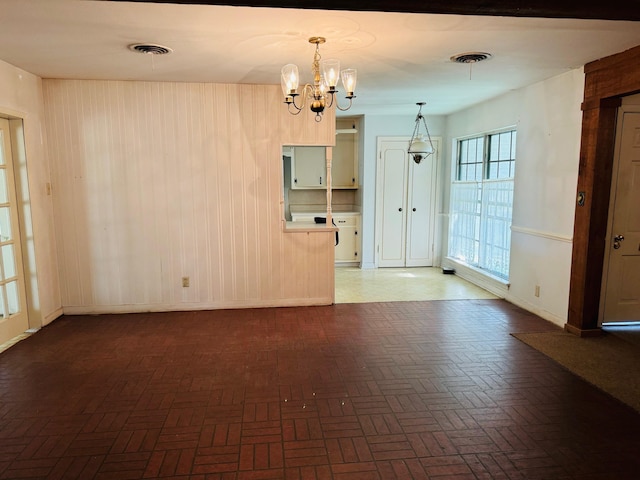 spare room with a chandelier and dark parquet flooring