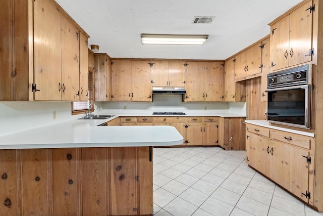 3785 Stanley Dr, Vidor, TX 77662 - kitchen with oven, under cabinet range hood, a peninsula, light countertops, and light tile patterned floors