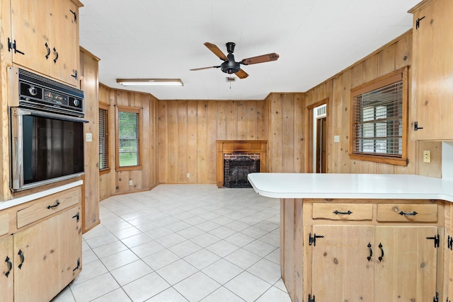 3785 Stanley Dr, Vidor, TX 77662 - kitchen featuring oven, a fireplace, a ceiling fan, light countertops, and light brown cabinetry