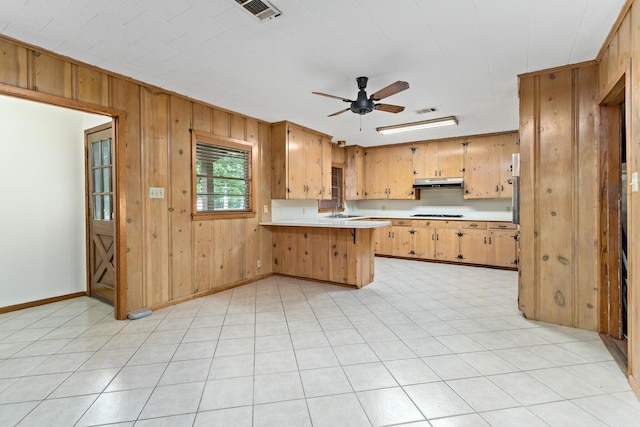 3785 Stanley Dr, Vidor, TX 77662 - kitchen with light countertops, a peninsula, wood walls, ceiling fan, and under cabinet range hood