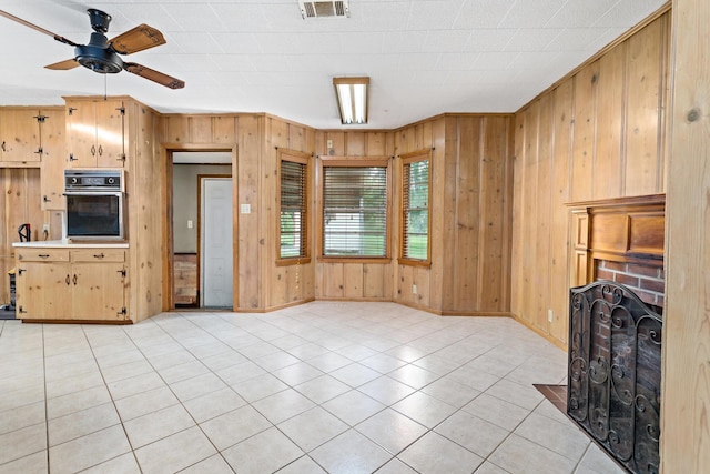 3785 Stanley Dr, Vidor, TX 77662 - unfurnished living room featuring wood walls, light tile patterned flooring, a ceiling fan, and a brick fireplace