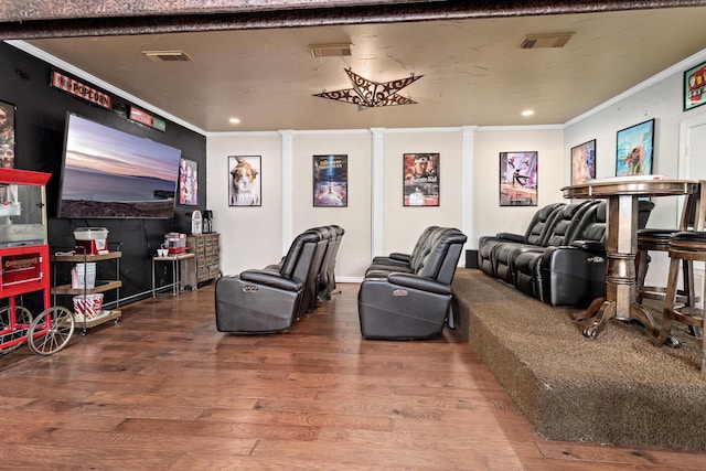 home theater room with wood-type flooring, decorative columns, and ornamental molding