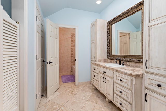 bathroom featuring vanity, a tub to relax in, and lofted ceiling