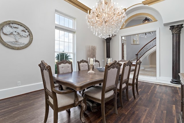 dining space with a high ceiling, dark hardwood / wood-style flooring, decorative columns, and an inviting chandelier