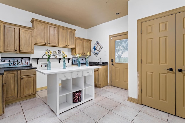 kitchen featuring sink, a kitchen island, a breakfast bar area, and light tile patterned flooring