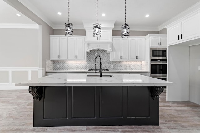 7705 Water Edge, Beaumont, TX 77707 - kitchen featuring white cabinetry, crown molding, light stone counters, a center island with sink, and decorative light fixtures