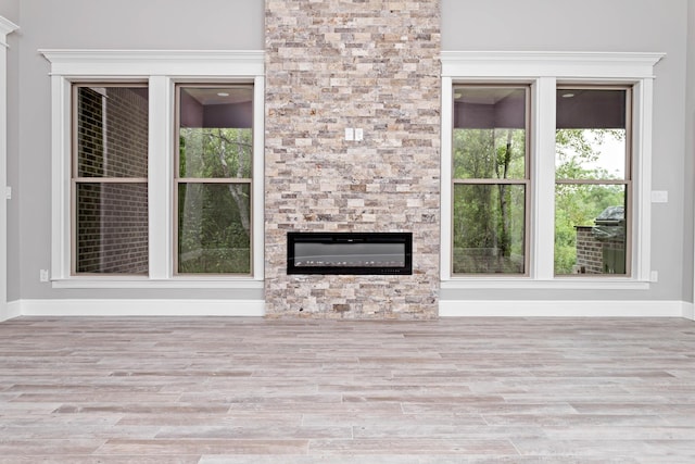 7705 Water Edge, Beaumont, TX 77707 - unfurnished living room featuring wood finished floors, baseboards, a fireplace, and plenty of natural light