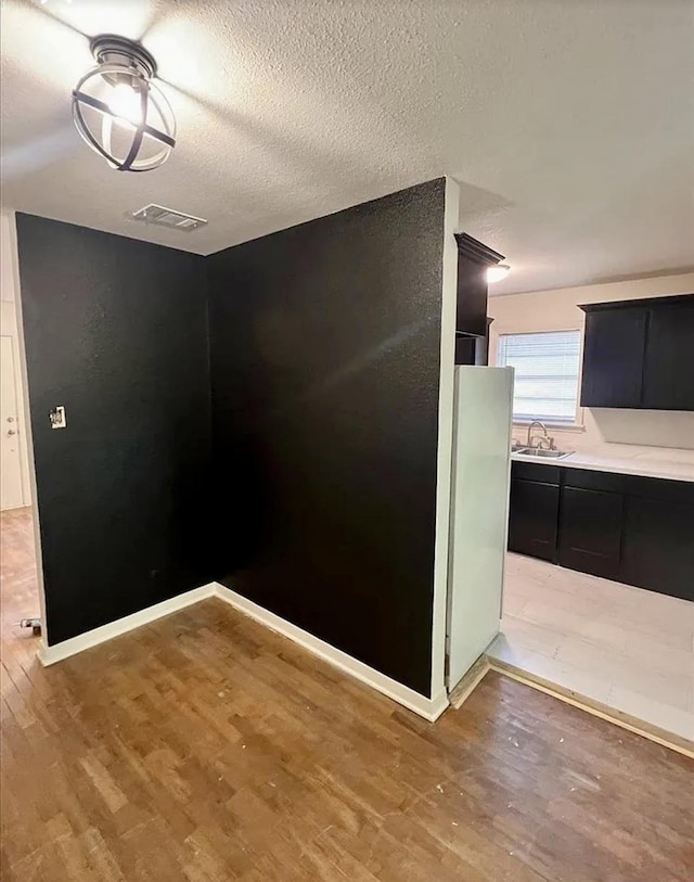 265 W Hartel St, Sour Lake, TX 77659 - empty room featuring light wood-type flooring, a sink, a textured ceiling, and baseboards