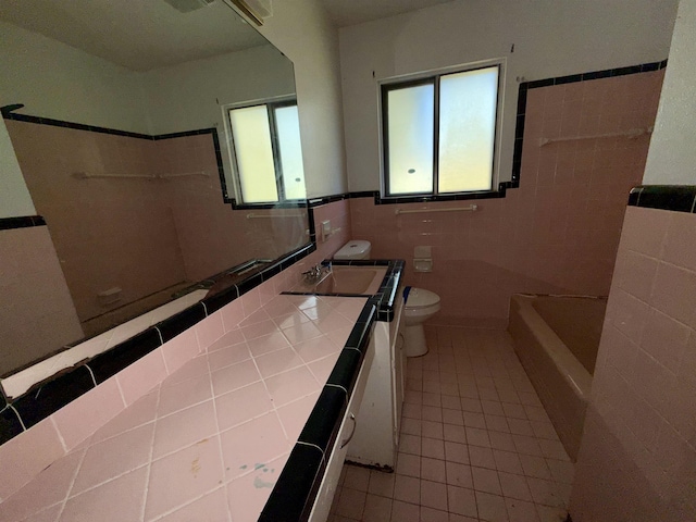 bathroom with vanity, tile walls, tile patterned flooring, toilet, and a tub