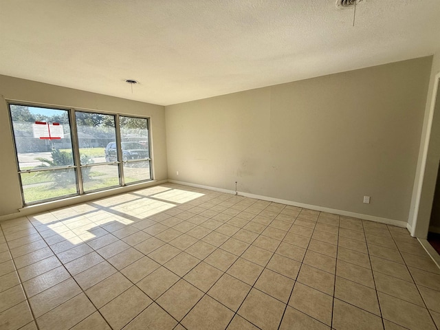 tiled empty room with a textured ceiling