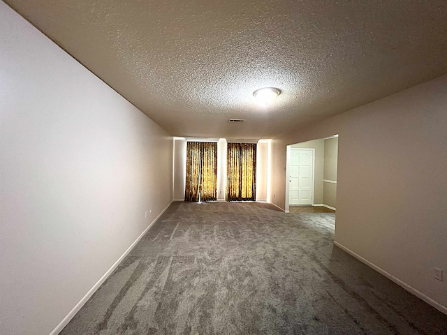 spare room with carpet floors, visible vents, baseboards, and a textured ceiling